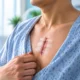 Incision Care After Chest Surgery | George thoracic Person in a hospital gown lifting the shirt to reveal a healing vertical chest incision secured with multiple adhesive bandages.